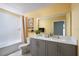 Bright bathroom with double sink vanity, gray cabinets, and a shower/tub combo with decorative curtain at 1233 Tidal St, Haines City, FL 33844