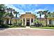 A grand clubhouse boasts impressive architecture, surrounded by manicured landscaping and stately palm trees under a bright sky at 2572 Robert Trent Jones Dr # 1235, Orlando, FL 32835