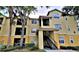 Inviting two-story condo building painted in yellow and cream tones, featuring stairs to the residences above at 2572 Robert Trent Jones Dr # 1235, Orlando, FL 32835