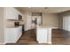 Open kitchen features white cabinets, stainless appliances, and a center island with wood flooring at 4106 Gerbera Daisy Ave, Lake Hamilton, FL 33851