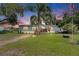 Charming single-story home with light blue siding, a cozy front porch, and a well-maintained lawn at dusk at 4854 Myrtle View N Dr, Mulberry, FL 33860