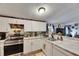 Modern kitchen featuring white cabinets, stainless steel appliances, and a view into the connected living area at 4854 Myrtle View N Dr, Mulberry, FL 33860
