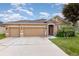 Charming single-story home with a well-manicured lawn, two-car garage, and inviting stone-accented entrance at , Kissimmee, FL 34758