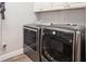 Laundry room with gray front load washer and dryer, overhead cabinets, and wood-look floors at 2242 Soaring Eagle Pl, Lake Mary, FL 32746