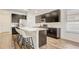 Modern kitchen with stainless steel appliances, island with bar stools, and wood-look tile flooring at 3067 Princewood Dr, Minneola, FL 34715