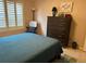Bedroom featuring shuttered windows, a wood dresser, and neutral colored walls at 310 Knoll Pl, The Villages, FL 32162