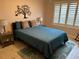 Bedroom with neutral walls, shuttered windows, and blue bedding with decorative throw pillows at 310 Knoll Pl, The Villages, FL 32162