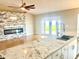 Modern kitchen open to the living room featuring granite countertops, stone fireplace, and natural light at 7144 Remington Oaks Loop, Lakeland, FL 33810