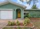 Inviting front entrance with a bright yellow door, complemented by lush landscaping and textured stucco at 1238 Honeytree E Ln, Lakeland, FL 33801