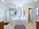 Bright bathroom featuring a corner tub, glass-enclosed shower, white tiled floors, and neutral walls at 449 Moscato Dr, Davenport, FL 33897
