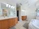 Bathroom featuring wood vanity, marble countertop, garden tub, and mirrors at 449 Moscato Dr, Davenport, FL 33897