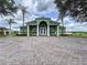 Green clubhouse with white columns, arched windows, double doors, and brick driveway at 449 Moscato Dr, Davenport, FL 33897