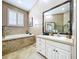 Bright bathroom featuring a soaking tub, large mirror, and plantation shutters at 776 Grasslands Village Cir # 776, Lakeland, FL 33803
