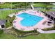 Aerial view of a community heart-shaped pool with lounge chairs, umbrellas and lush tropical landscaping at 776 Grasslands Village Cir # 776, Lakeland, FL 33803