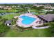 Aerial view of a community heart-shaped pool with lounge chairs, umbrellas and lush tropical landscaping at 776 Grasslands Village Cir # 776, Lakeland, FL 33803