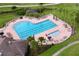 Aerial view of a community heart-shaped pool with lounge chairs, umbrellas and lush tropical landscaping at 776 Grasslands Village Cir # 776, Lakeland, FL 33803