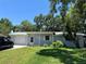 Charming single-story home with a well-maintained lawn and mature trees in a suburban setting with blue sky at 835 5Th St, Port Orange, FL 32129