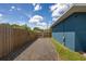 Gravel driveway leading to a wooden gate and fenced yard with a blue home to the side at 3983 Shay Dr, Bartow, FL 33830