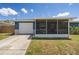 Charming home with a blue exterior, white garage door, and screened front porch with ample greenery at 3983 Shay Dr, Bartow, FL 33830