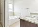 A bathroom features a white tub and a single sink with granite countertops at 547 Sardinia Cir, Davenport, FL 33837