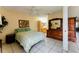 Main bedroom with tile floors, ceiling fan, dresser, and a glimpse into the en-suite bathroom at 62 Lakepointe Cir, Kissimmee, FL 34743