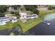 Stunning aerial view of lakefront home with solar panels, lush lawn, private dock, and a detached garage at 124 Pangola Dr, Winter Haven, FL 33880