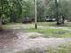 A view of the backyard with grass, trees, and a home visible in the distance at 12828 Sw 49Th Ter, Webster, FL 33597