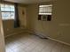 A simple bedroom featuring tile floors, two windows, and an air conditioning unit at 12828 Sw 49Th Ter, Webster, FL 33597