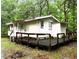 Exterior view of the house featuring a large wooden deck; greenery and trees provide a natural setting at 12828 Sw 49Th Ter, Webster, FL 33597
