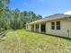 Backyard featuring a well-maintained lawn and patio with sliding glass doors, surrounded by lush trees at 19041 Mardi Gras St, Orlando, FL 32833