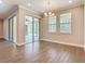 Bright dining room with wood floors, a chandelier, and sliding glass doors to the screened in patio, with a wooded view at 19041 Mardi Gras St, Orlando, FL 32833
