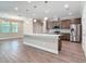 Gourmet kitchen with stainless appliances, granite countertops, a large island, and wood floors flowing into the living room at 19041 Mardi Gras St, Orlando, FL 32833