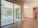 Bright living room with wood floors and sliding glass doors to an outdoor screened in patio and view of wooded backyard at 19041 Mardi Gras St, Orlando, FL 32833