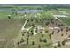 Picturesque aerial view of the property with a well-maintained lawn, mature trees, and a serene pond nearby at 9419 Alturas Babson Park Cutoff Rd, Bartow, FL 33830