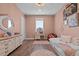 Bedroom with pink walls, hardwood floors, decorative art, daybed, dresser with mirror and vanity with makeup mirror at 9419 Alturas Babson Park Cutoff Rd, Bartow, FL 33830