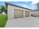 A detached, two-car garage has white siding and tan garage doors with black iron hardware at 9419 Alturas Babson Park Cutoff Rd, Bartow, FL 33830