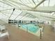 Bright indoor pool area with a skylight, clear water, and plenty of space for swimming laps or relaxing at 5402 Rosewall Cir, Leesburg, FL 34748