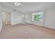 Inviting living room featuring neutral carpet and walls, bright window, ceiling fan, and access to other rooms at 5402 Rosewall Cir, Leesburg, FL 34748