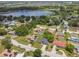 Overhead view of a home nestled among mature trees, featuring a well-kept lawn, and a neighborhood with a lake nearby at 1003 Edmund Ave, Dundee, FL 33838