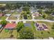 A landscape aerial view of a house with a tidy yard and a surrounding neighborhood filled with lots of shady green trees at 1003 Edmund Ave, Dundee, FL 33838