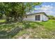 White house with sliding glass door and grassy backyard with mature shade trees at 1003 Edmund Ave, Dundee, FL 33838