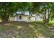 White house with sliding glass door and grassy backyard with mature shade trees at 1003 Edmund Ave, Dundee, FL 33838