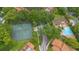 Aerial view featuring community tennis courts, swimming pool, manicured grounds, and mature trees at 1038 E Michigan St # 1, Orlando, FL 32806