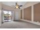 Neutral carpeted bedroom featuring a ceiling fan, balcony access, and decorative wall panels at 1038 E Michigan St # 1, Orlando, FL 32806