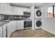 The kitchen features white cabinets, stainless steel appliances, stacked washer/dryer, and hardwood floors at 1038 E Michigan St # 1, Orlando, FL 32806