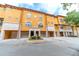 Attractive yellow townhouse featuring individual garages and stone accents at 6133 Metrowest Blvd # 105, Orlando, FL 32835