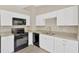 Modern kitchen features white cabinets, granite countertops, and black appliances at 562 Nardello Dr, Deltona, FL 32725