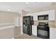 Contemporary kitchen with white cabinets, black appliances, and a view of the living area at 562 Nardello Dr, Deltona, FL 32725