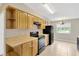 Well-lit kitchen featuring ample cabinet space, black appliances, and a view to the front yard at 6906 Cocos Dr, Orlando, FL 32807