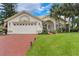 Charming single-story home with a two-car garage, brick driveway, and lush green lawn at 414 Long Cove Ct, Ormond Beach, FL 32174